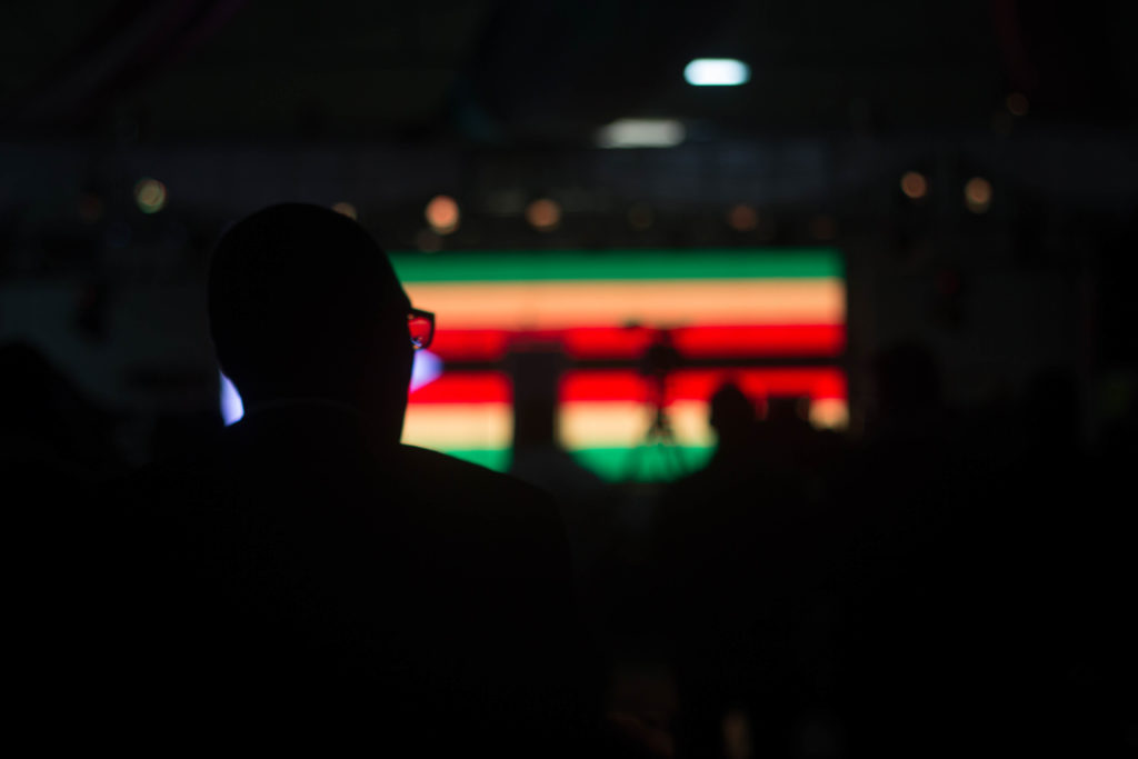 A man is silhouetted in front of a giant screen during a welcome dinner party in the evening